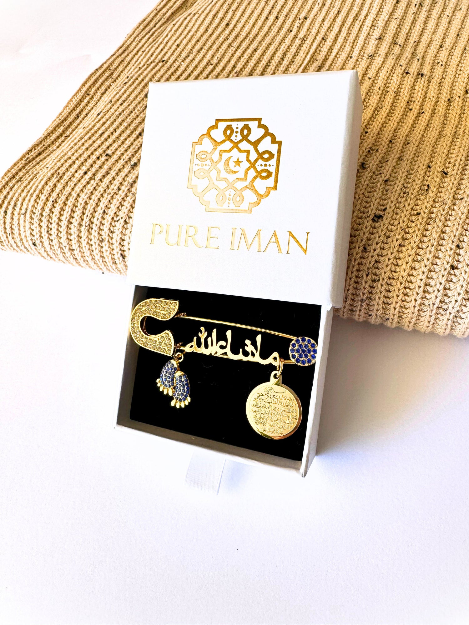 Ayatul Kursi pin with beige speckled blanket, which are included in our Muslim baby gift boxes